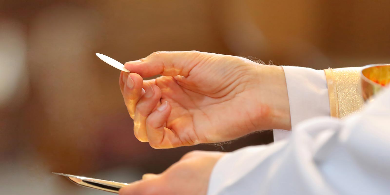 A priest hand presenting the Eucharist