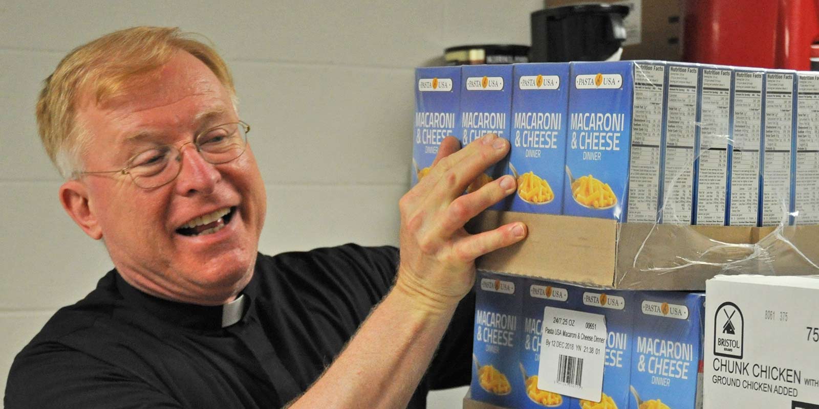 O padre Robert ajuda a organizar comida para os pobres em sua paróquia.