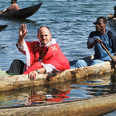 Father Pawel Gala being taken by boat to a fisherman feast in Anilavinany, Madagascar