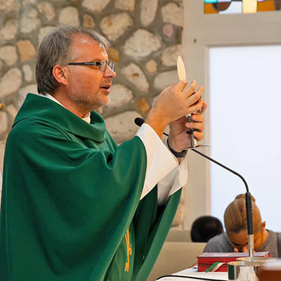 Father Adam elevating celebrating mass with the Eucharist