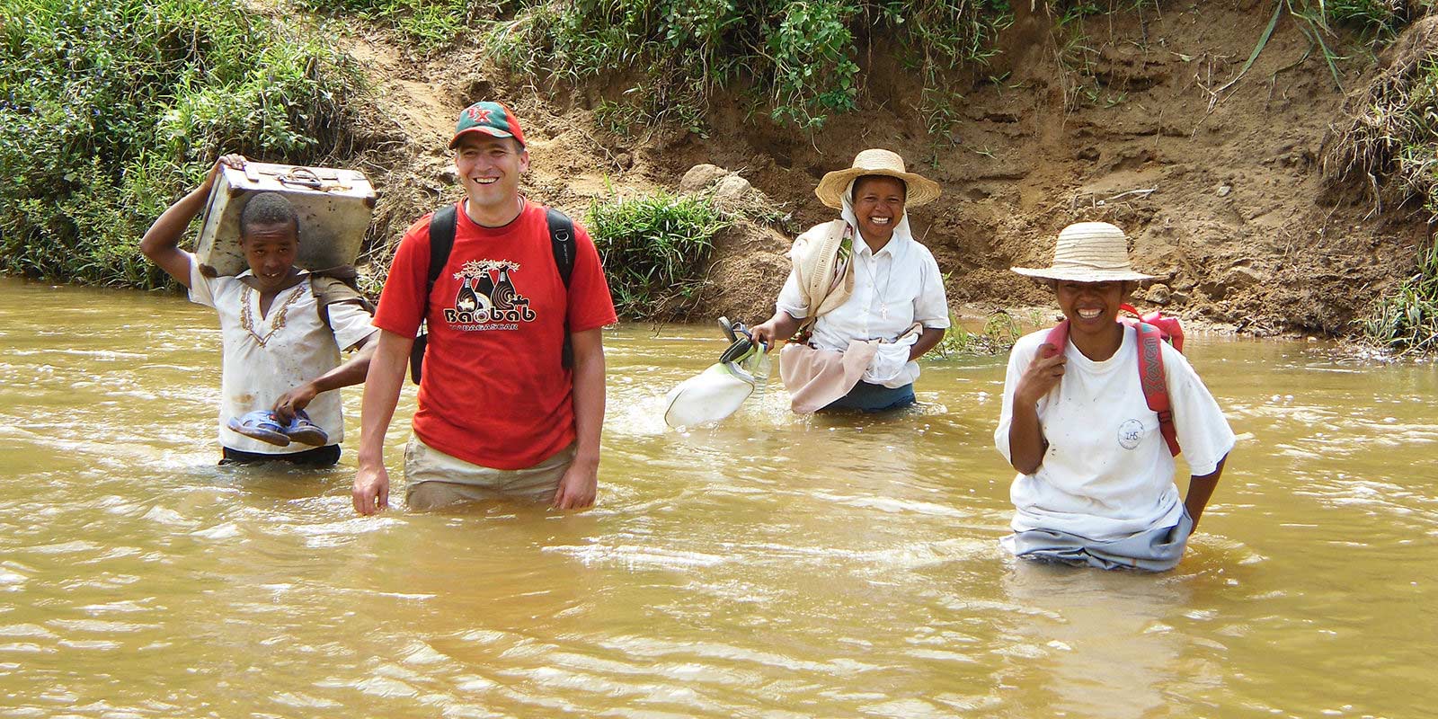 O padre Andrzej Dzida atravessa a água durante uma patrulha missionária em Madagascar.