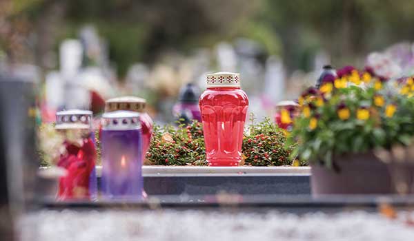 Candle burning near grave for All Souls Day