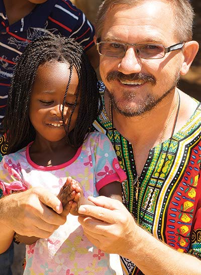 Padre Grad en Madagascar, dobla las manos de una niña para rezar