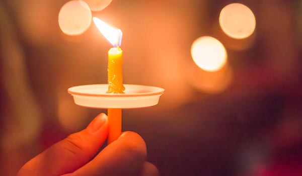 Hand holding a memorial candle - 600x350.jpg