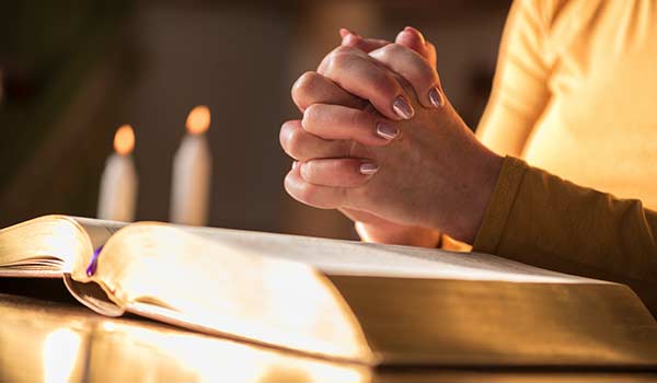 Hands pray over a bible