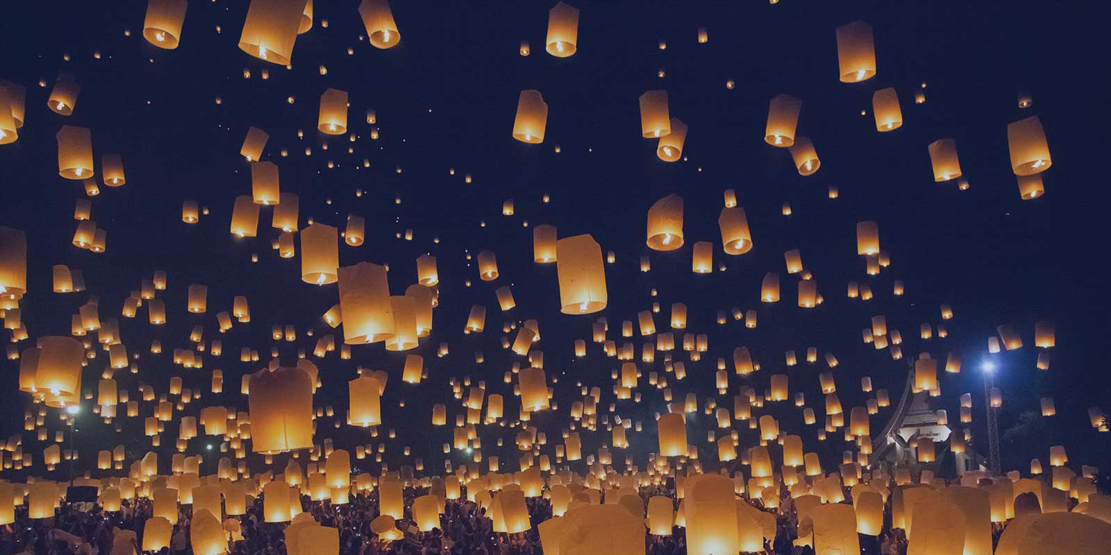 Night sky full of lighted, floating paper lanterns.