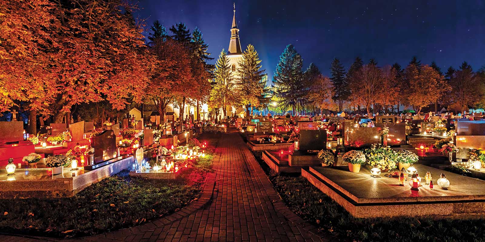 Cemetery lit up at night with a chapel in the back.