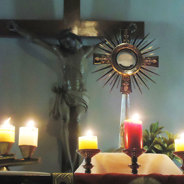 Najświętszy sakrament w monstrancji, krzyż i świece
