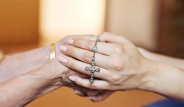 Two people holding hands with rosary - 350x600
