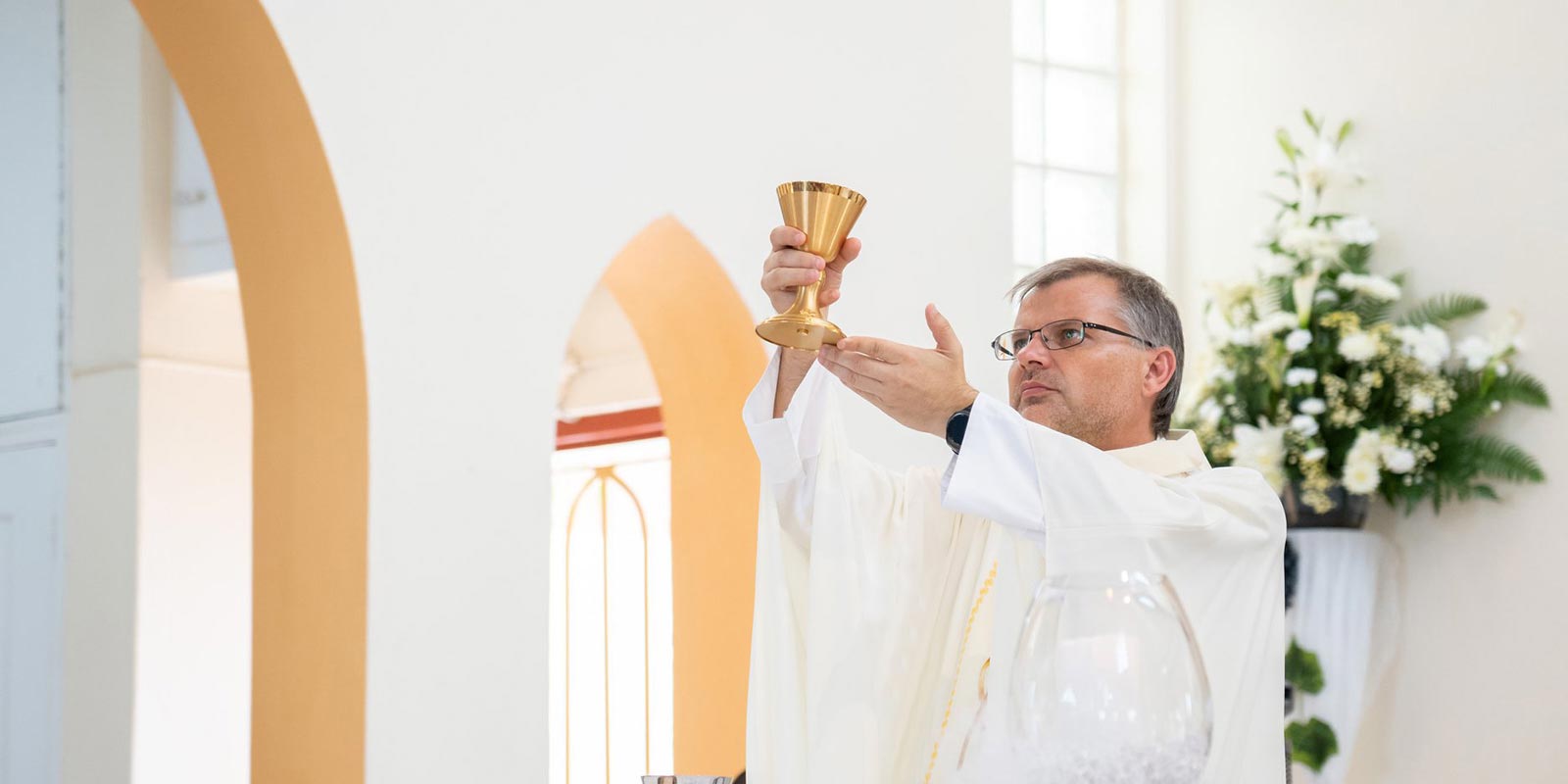 El padre Adam levanta el cáliz durante la misa. en St. Maarten