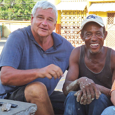 Brother Bernie Spitzley sitting with a local resident in Jamaica